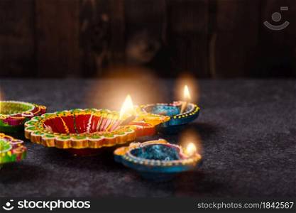 Close up of clay lit light a fire already on Diya or oil lamp, studio shot on concrete background, Decoration of Hinduism rangoli, Happy celebration Deepavali or Diwali festival concept