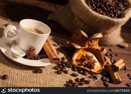 Close-up of coffee cup with star anise, cinnamon and dried orange fruit