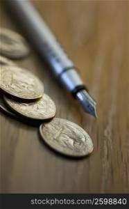 Close-up of coins with a fountain pen