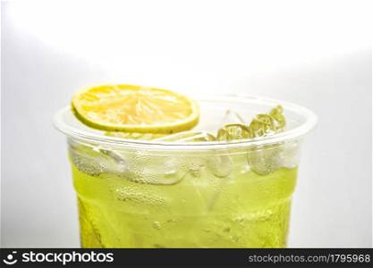 Close up of cold lemonade in plastic glass on white background