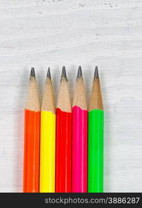 Close up of colorful sharpen pencil tips on white desktop. Layout in vertical format.