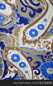 Close-up of colorful vintage fabric with blue and brown paisley printed on polyester.