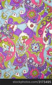 Close-up of colorful vintage fabric with flowers and shapes printed on polyester.