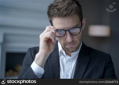 Close up of concentrated handsome austrian businessman dressed in suit adjusting glasses while working in office, executive man in spectacles at workplace. Business people concept. Concentrated handsome austrian businessman dressed in suit adjusting glasses while working in office