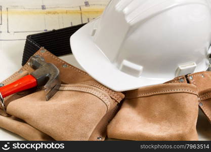 Close up of construction contractor tools with blurred out blue print drawings in background.