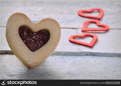 Close-up of cookie with jam and three red paper hearts
