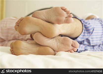 Close Up Of Couple&acute;s Feet Relaxing On Bed At Home