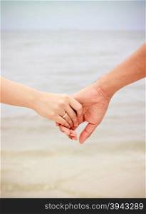 Close up of couple holding hands on the beach