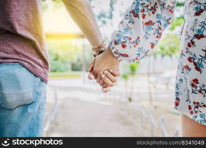 Close up of couple holding hands outdoors, Close up of young couple walking holding hands. Close-up of teenagers holding hands in a park. View of young couple holding hands outdoors