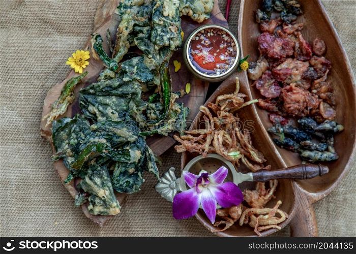 Close-up of Crispy Flowers, Crispy Herbs and Crispy Vegetables served with Sweet sauce in a Wooden tray, copy space.