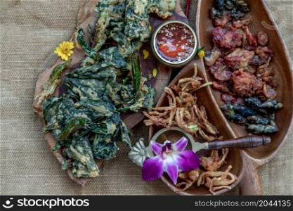 Close-up of Crispy Flowers, Crispy Herbs and Crispy Vegetables served with Sweet sauce in a Wooden tray, copy space.