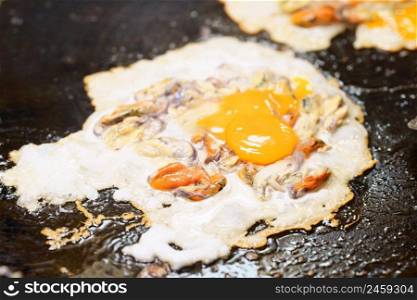 Close-up of Crispy Fried Mussel Pancake or Mussel Omellette on hot pan, thai street food market