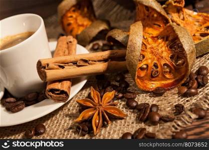 Close-up of cup of coffee with cinnamon, dried orange fruit and star anise