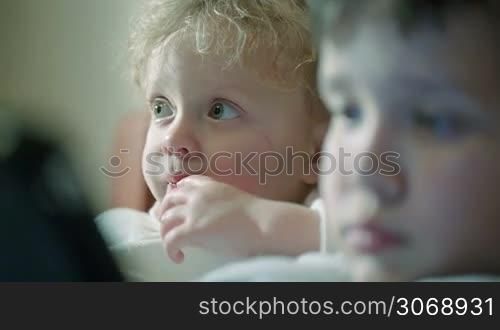 Close-up of curious children faces. At first focus on the girl staring at something, then on the boy with touchpad