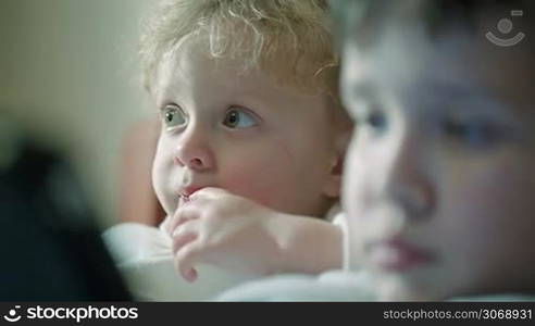 Close-up of curious children faces. At first focus on the girl staring at something, then on the boy with touchpad