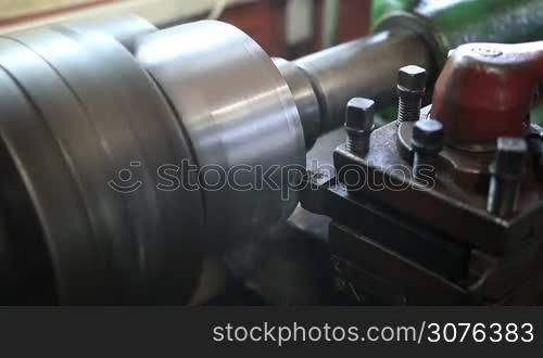 Close up of cutting tool processing on old lathe machine in workshop.