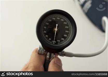 Close up of display of sphygmomanometer, held by male hand