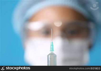 Close-Up Of doctor holding Syringe Against blue Background