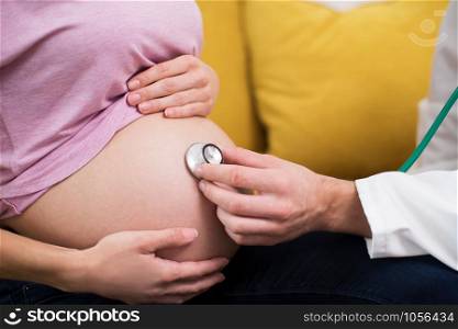 Close Up Of Doctor Using Stethoscope To Examine Pregnant Woman