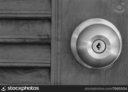 close up of doorknob with wooden door, black and white tone