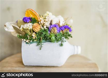 Close-up of dried flowers and fir tree branches potted in painted white bottle