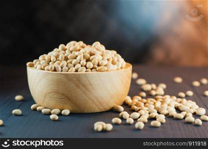 close up of dried soybeans in a wooden bowl on table with dark background