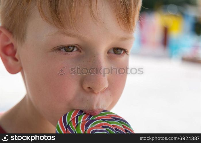 Close up of Eight Years Child Licking Colorful Round Lollipop