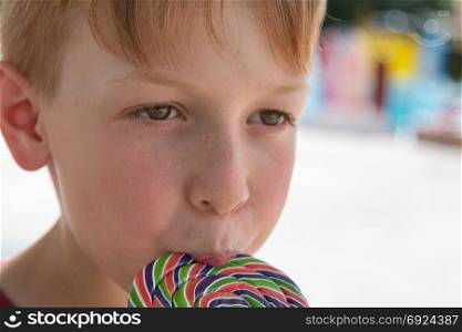 Close up of Eight Years Child Licking Colorful Round Lollipop