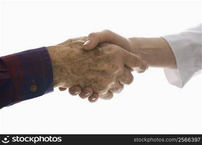 Close-up of elderly Caucasian male shaking hands with mid-adult Caucasian female hand.