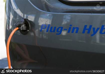 Close up of electrical plug recharging electric car