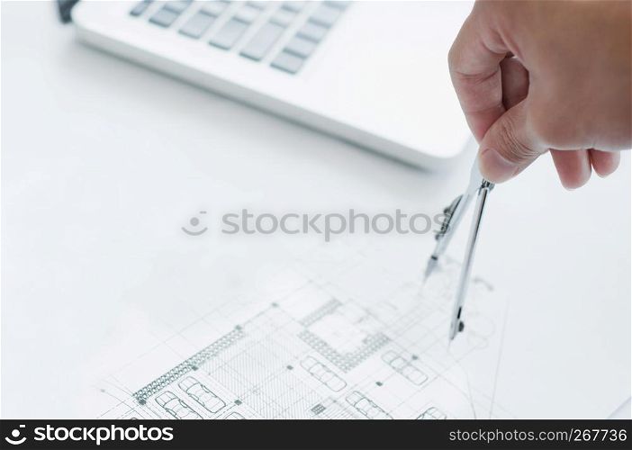 Close up of engineer hand sketching a construction project with Laptop at the workplace