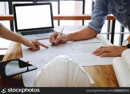 Close up of engineer hands discussing a building construction project with blank screen laptop at workplace
