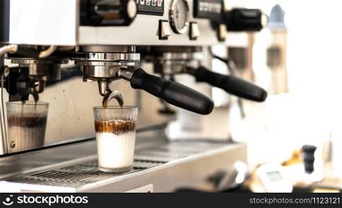 Close-up of espresso top white milk pouring from automatic coffee machine. Professional coffee brewing.Espresso coffee and milk help to feel refreshed at work or to relax on the weekends.