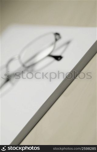 Close-up of eyeglasses and a notepad on the table