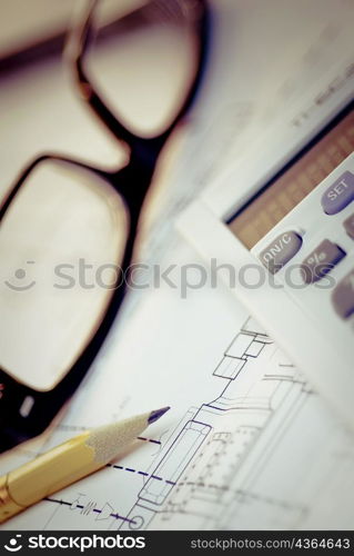 Close-up of eyeglasses and a pencil on a blueprint