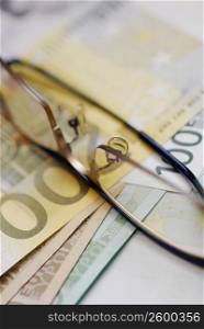 Close-up of eyeglasses on an one hundred Euro banknote