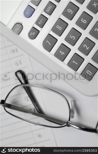 Close-up of eyeglasses with a calculator on a diary