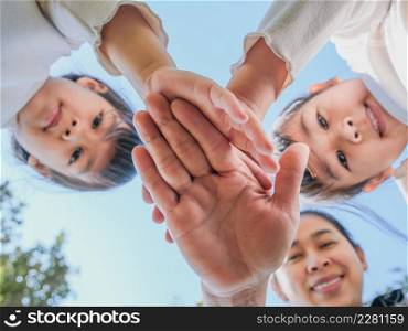 Close up of family hands put their hands together against blue sky background on a warm sunny day. Happy people or team participation.