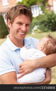 Close Up Of Father Cuddling Newborn Baby Boy Outdoors At Home