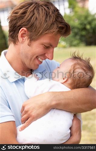 Close Up Of Father Cuddling Newborn Baby Boy Outdoors At Home