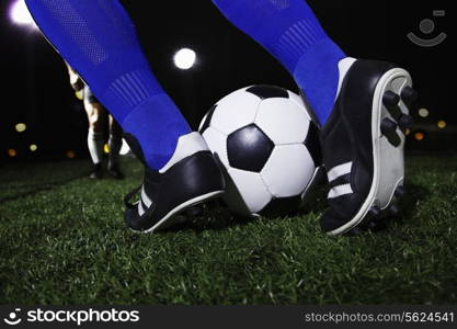 Close up of feet kicking the soccer ball, night time in the stadium