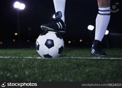 Close up of feet on top of soccer ball on the line, night time in the stadium