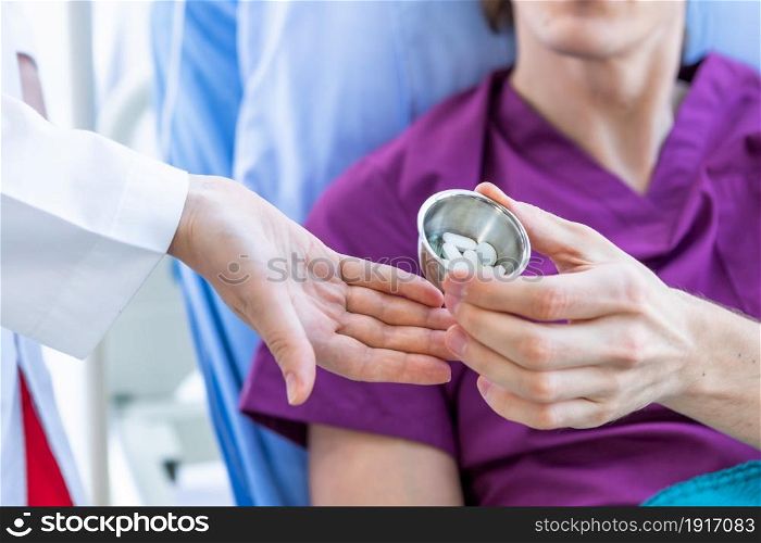 Close-up of Female doctor therapeutic advising Give Different tablets, pills, medications drugs to a man patient on bed for better healing In the room hospital background.