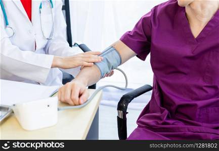 Close-up of female doctor with measuring the pressure to the arm of a man patient wear arm with Digital pressure gauge for better healing In the room hospital background.