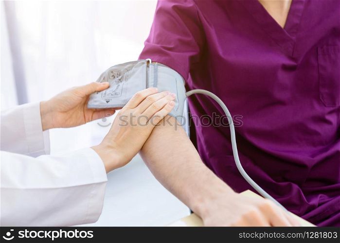 Close-up of female doctor with measuring the pressure to the arm of a man patient wear arm with Digital pressure gauge for better healing In the room hospital background.