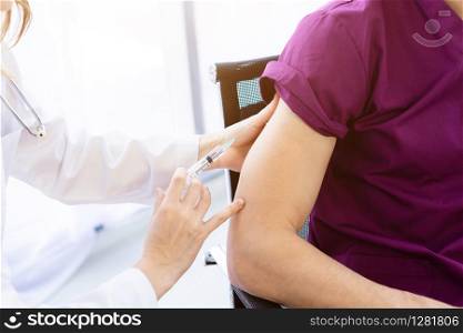 Close-up of female doctor with syringe to the arm of a man patient on Bed for better healing In the room hospital background.