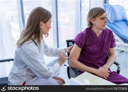 Close-up of female doctor with syringe to the arm of a man patient sit in a wheelchair for better healing In the room hospital background.