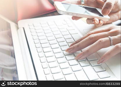 Close up of female hand using mobile phone and laptop computer, Working woman and Online shopping concept