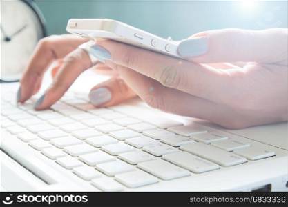 Close up of female hand using mobile phone and laptop computer, Working woman and Online shopping concept