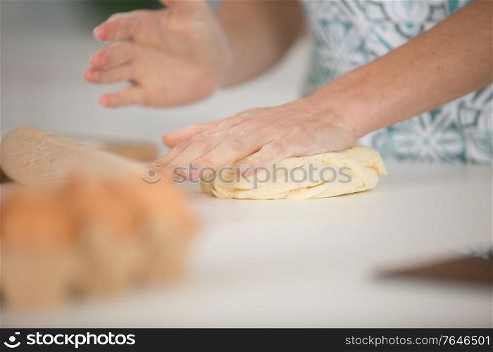 close up of female hands kneading dough at home